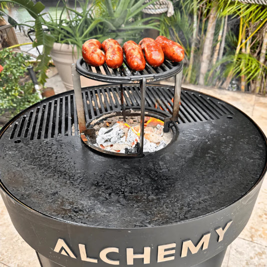 Black cast iron alchemy elevated rack with circular cooking grate holding sausages for grilling ALC003