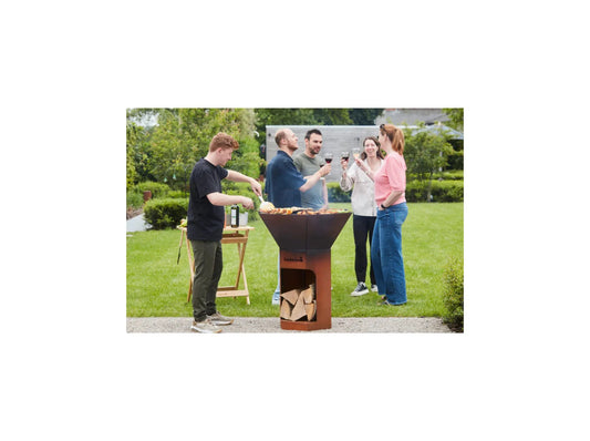 Rust-colored corten steel outdoor grill with conical cooking chamber and built-in wood storage compartment by barbecook