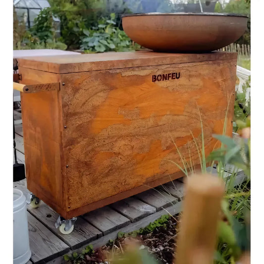 Rust-colored metal fire pit box with bonfeu branding and wooden handles featuring a weathered textured surface