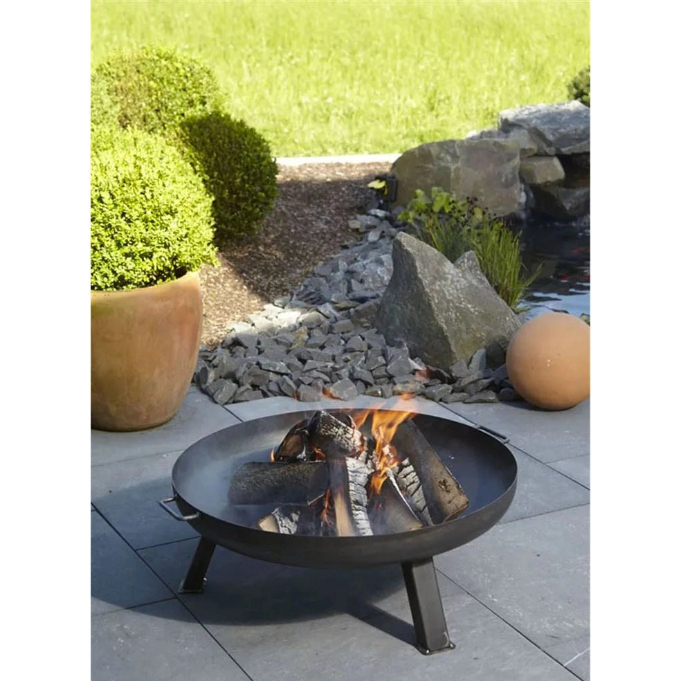 Buschbeck Ifen steel fire pit 80cm black metal with three legs and a circular bowl containing burning logs