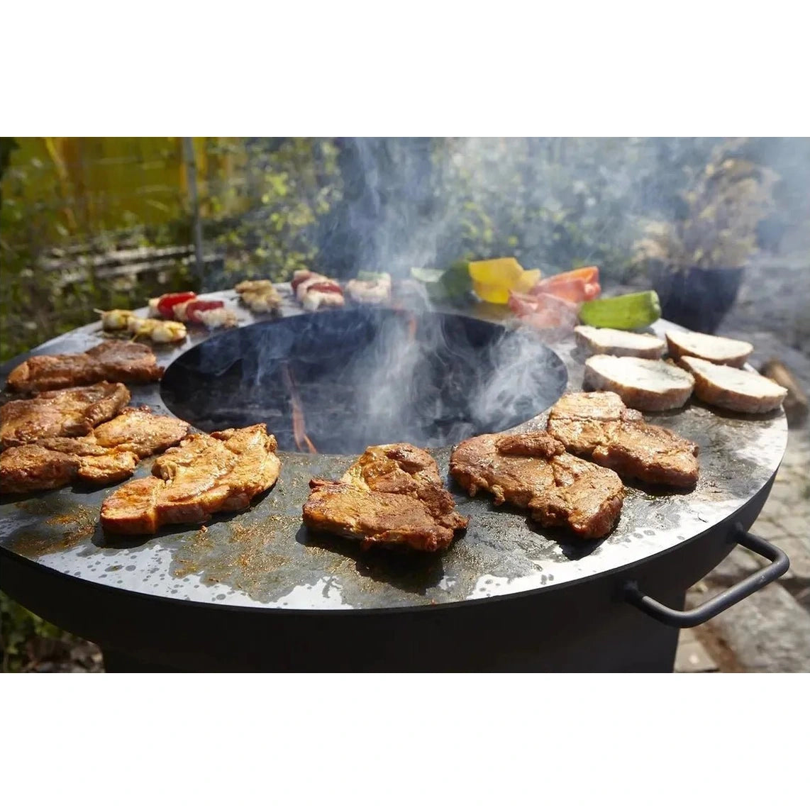 Black circular Buschbeck Plancha cooking ring with flat surface and side handles for 80cm outdoor fire pits with smoke