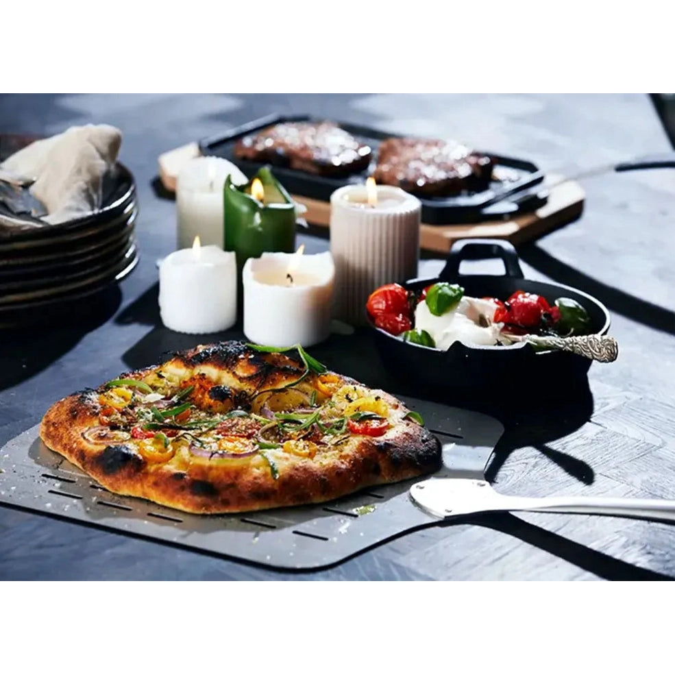 A freshly baked golden-brown pizza with colorful toppings on a metal spatula from Cozze 13 inch premium rotate gas pizza oven
