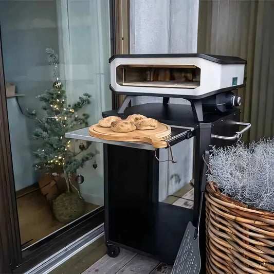 Black and white electric pizza oven with stainless steel side tray and freshly baked bread on wooden board cozze outdoor table