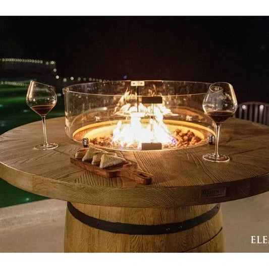 Elementi Lafite barrel bar fire table with round wooden top, built-in 13.2 kW fire pit, clear glass enclosure, and barrel base
