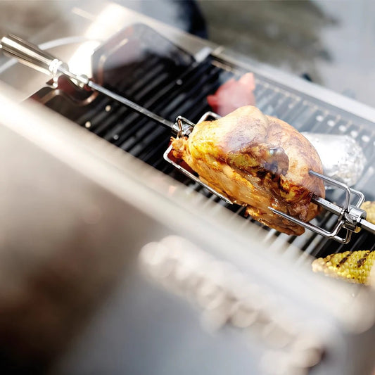 Golden-brown roasted chicken on stainless steel rotisserie spit over grill in Enders Kansas Pro 4 rotisserie kit EN7976