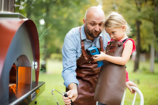 Blue and black non-contact infrared thermometer held by a child for use with fontana margherita anthracite wood-fired pizza oven