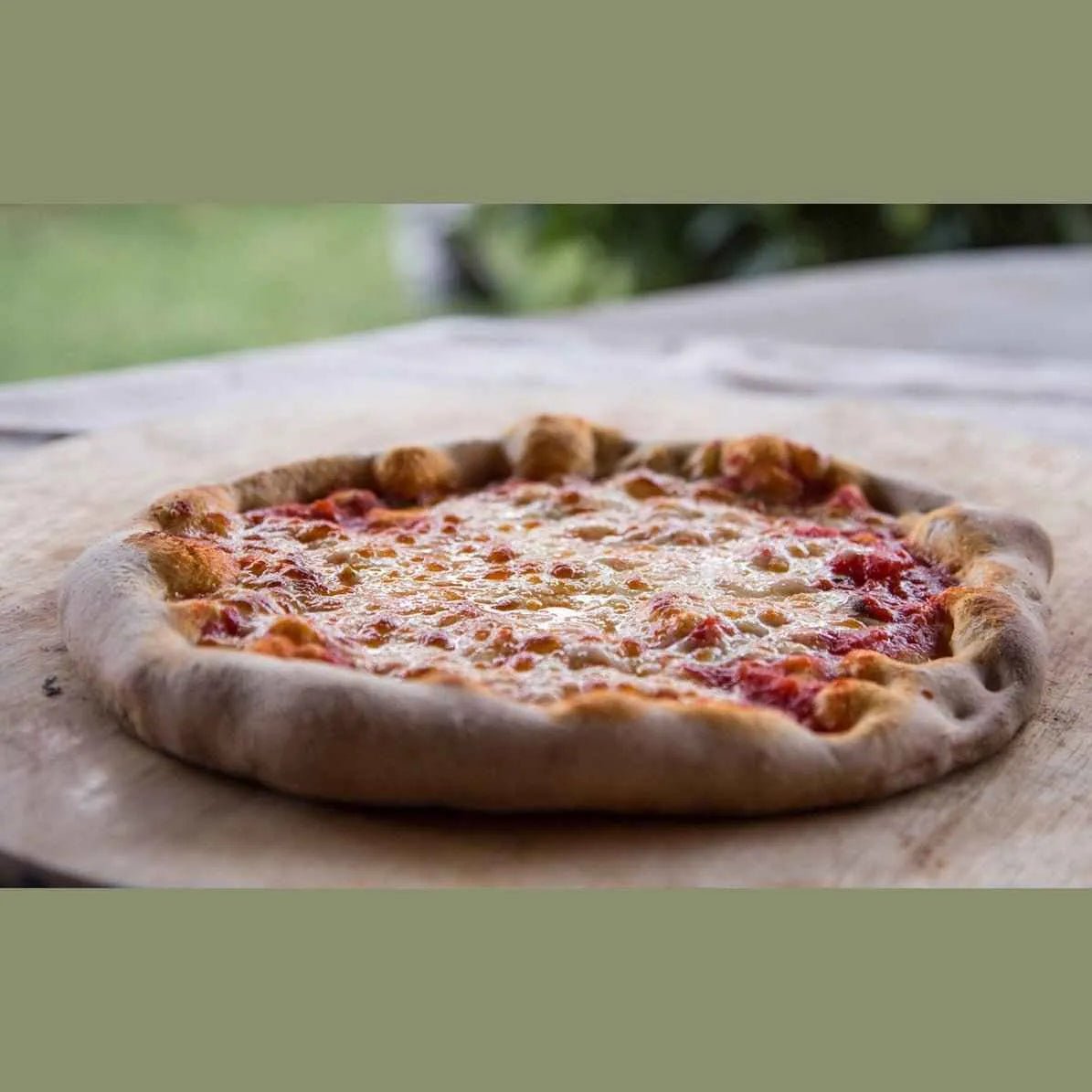 A freshly baked cheese pizza with golden crust in a fontana marinara anthracite dual fuel countertop pizza oven