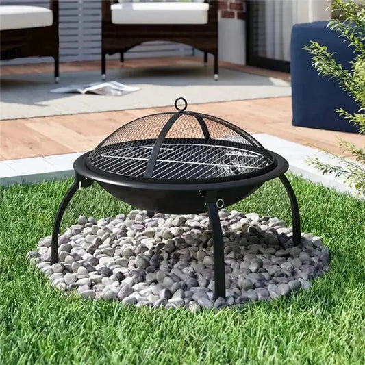 Black metal kaida traveller portable folding fire pit with mesh lid and tripod legs on gray pebbles