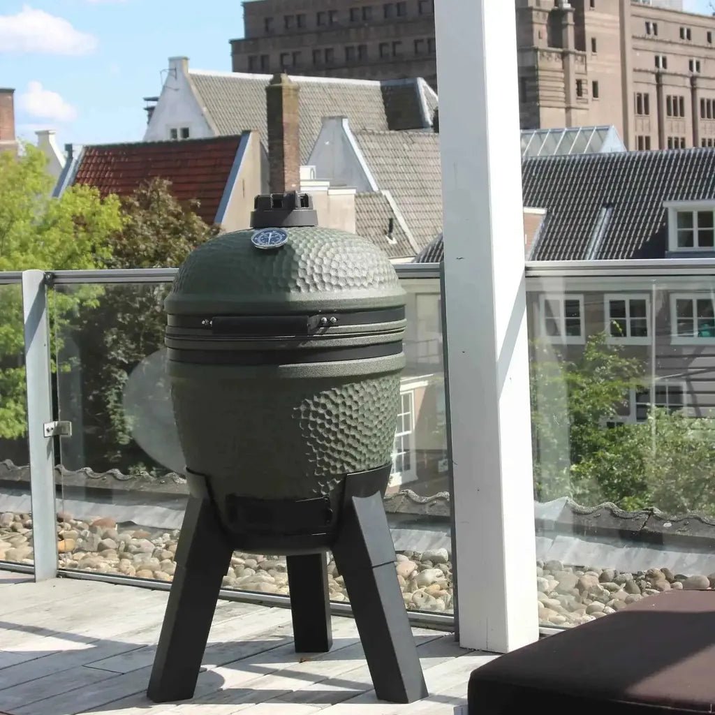 Olive green textured ceramic moddern kamado pedestal grill with black metal legs and circular lid made of aluminium