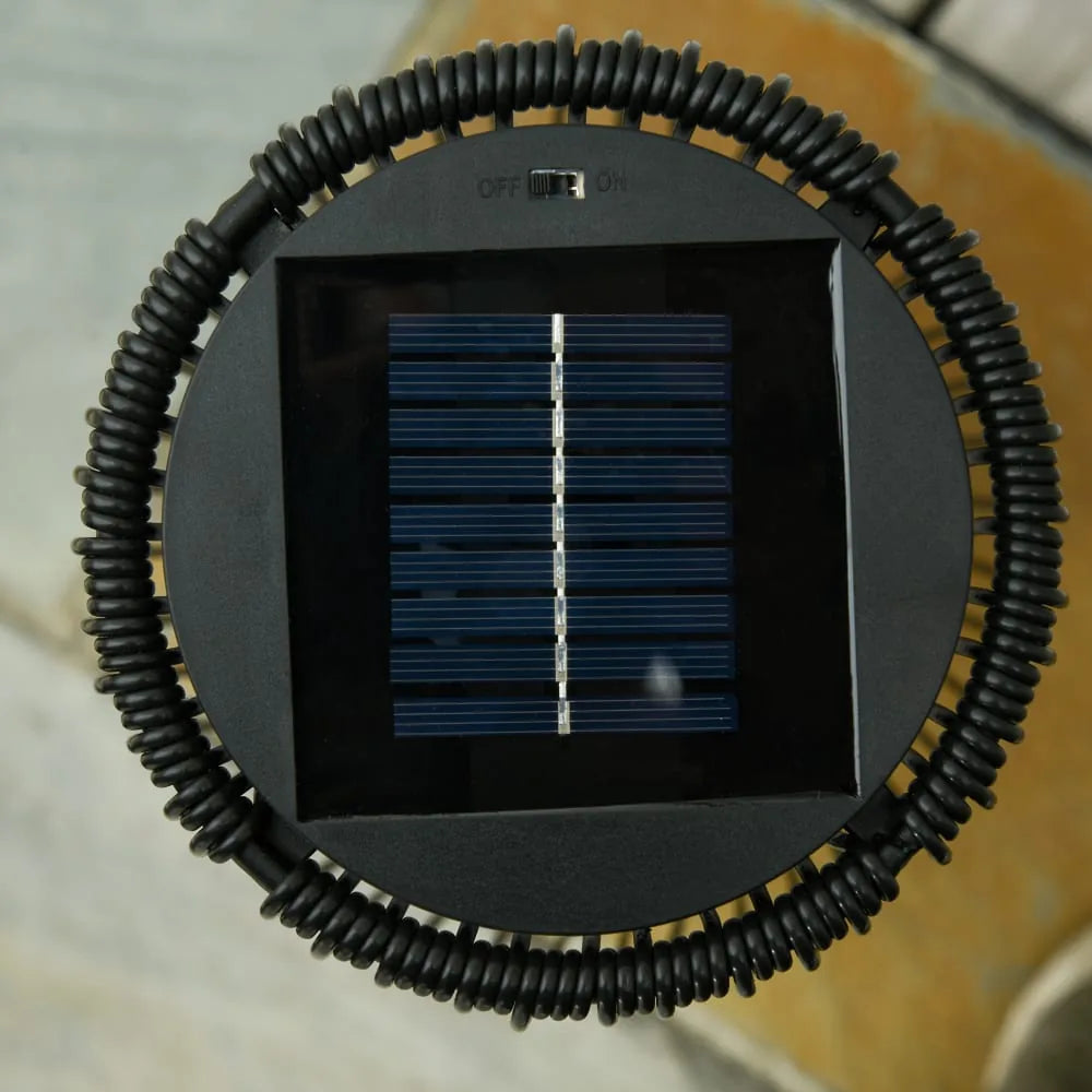 Outsunny solar powered woven resin wicker lantern black showing gold circular lens with black central aperture