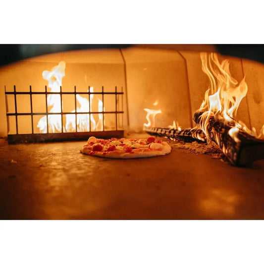 A freshly baked cheese pizza with toppings glows inside a wood-fired oven for outdoor cooking enthusiasts.