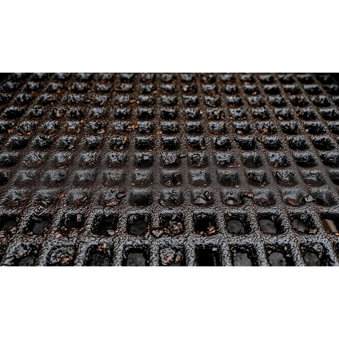 Black rubber BBQ mat with textured grid pattern designed for easy cleaning and maintenance of grills