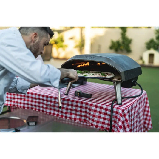 Black portable pizza oven with stainless steel legs and visible flame for mastering outdoor cooking tips