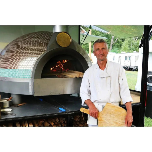 Stainless steel and mosaic-tiled wood-fired pizza oven with gold circular vent for solving outdoor cooking challenges