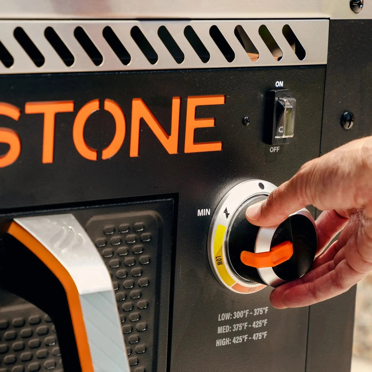 Blackstone 28 inch portable propane grill with black and orange stone body and silver vented panel with orange handle knob