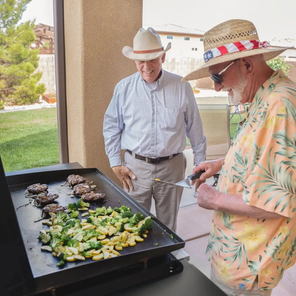Black Blackstone 36 inch griddle with air fryers cooking seared meat and sautéed vegetables on a black steel surface