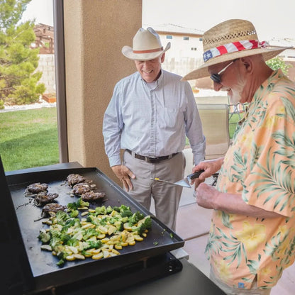 Black Blackstone 36 inch griddle with air fryers cooking seared meat and sautéed vegetables on a black steel surface