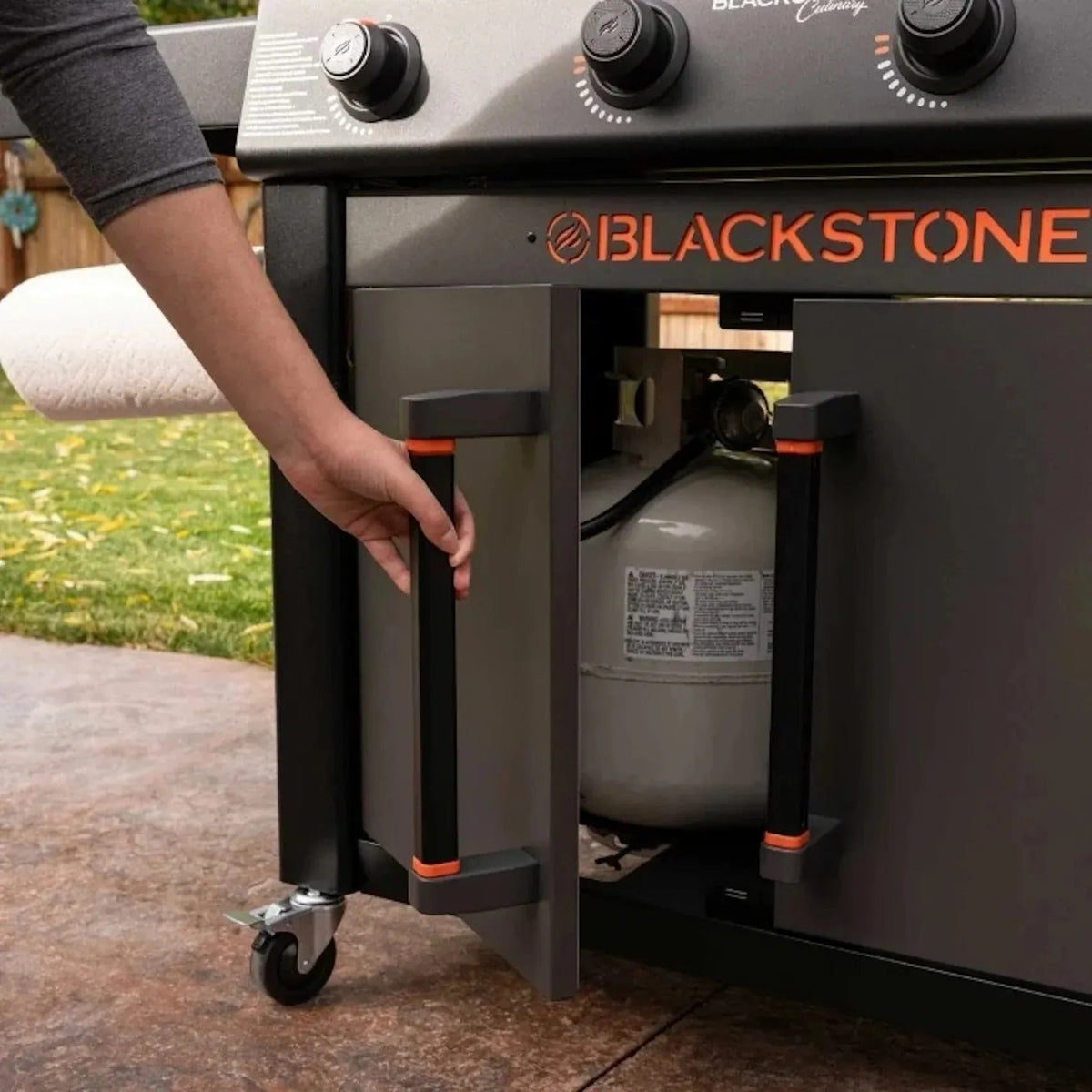 Blackstone culinary 36 inch griddle with cabinet and side table in black and orange featuring gas tank storage inside cabinet