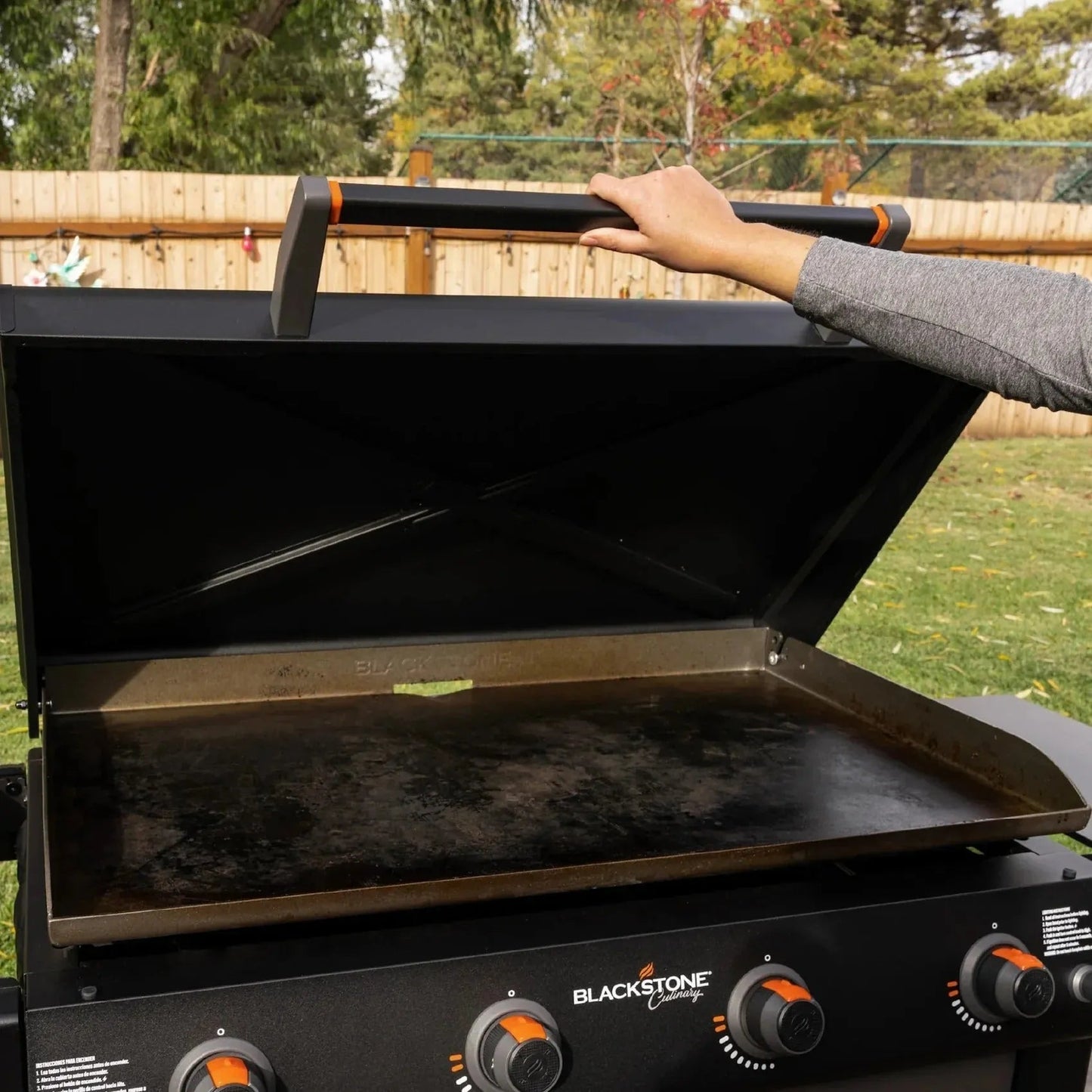 Blackstone culinary 36 inch griddle with cabinet and side table features a black cast iron cooking surface and orange knobs
