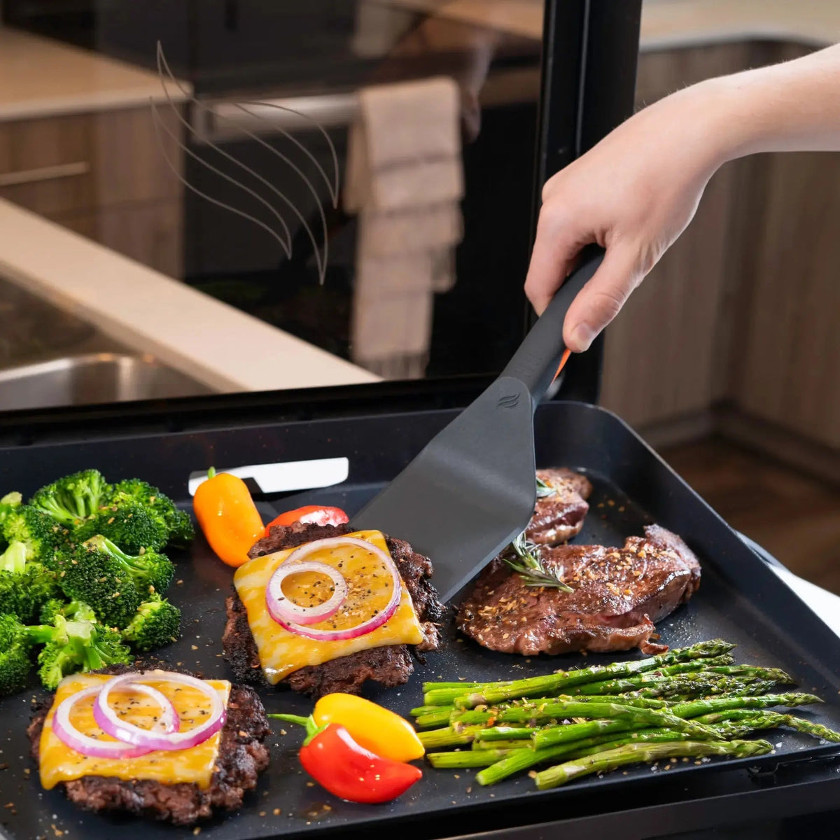 Black non-stick spatula with ergonomic handle flipping steak on blackstone e-series 17 inch electric griddle