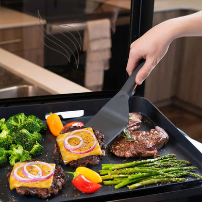 Black non-stick spatula with ergonomic handle flipping steak on blackstone e-series 17 inch electric griddle