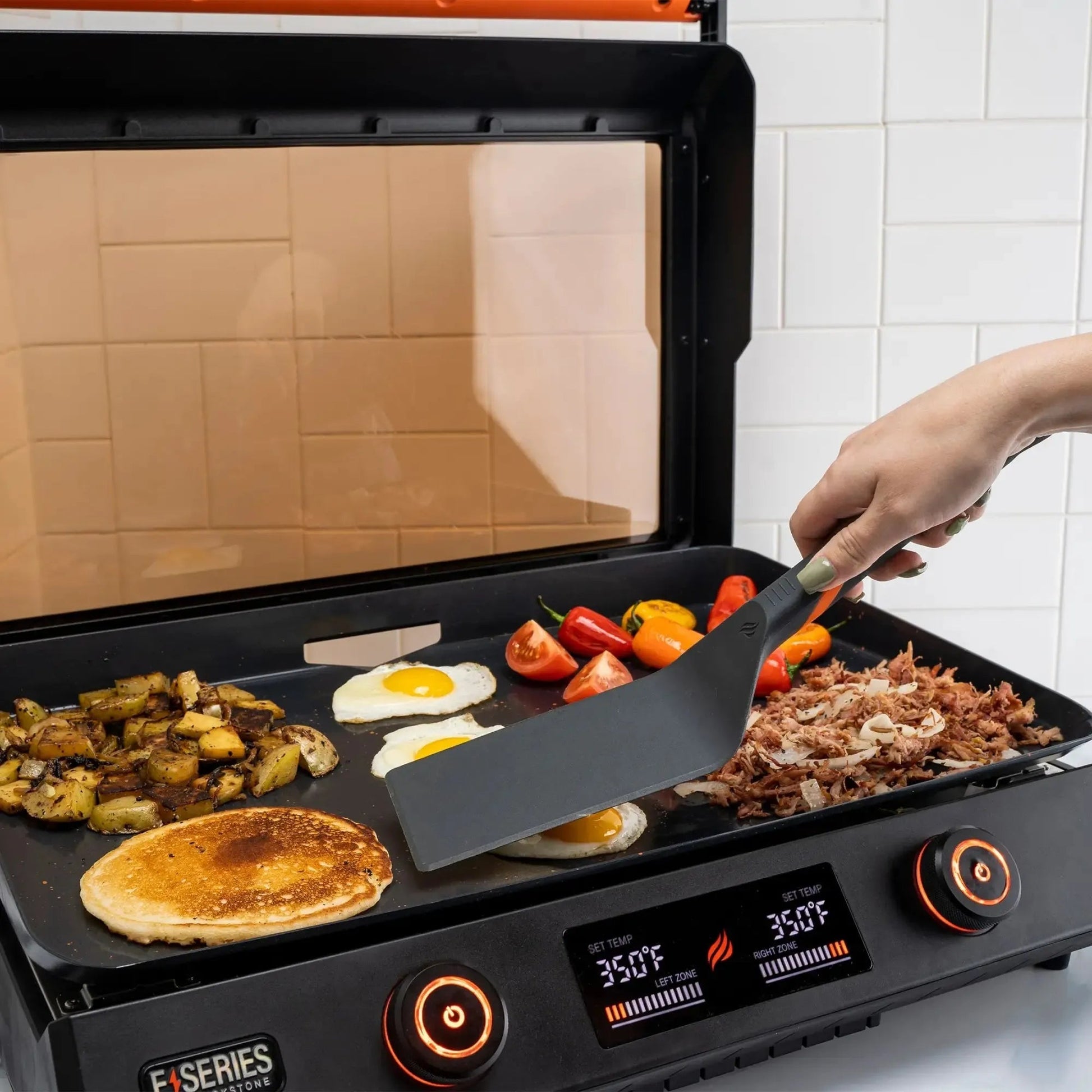 Blackstone E-Series black electric griddle with orange controls and digital display for versatile cooking use