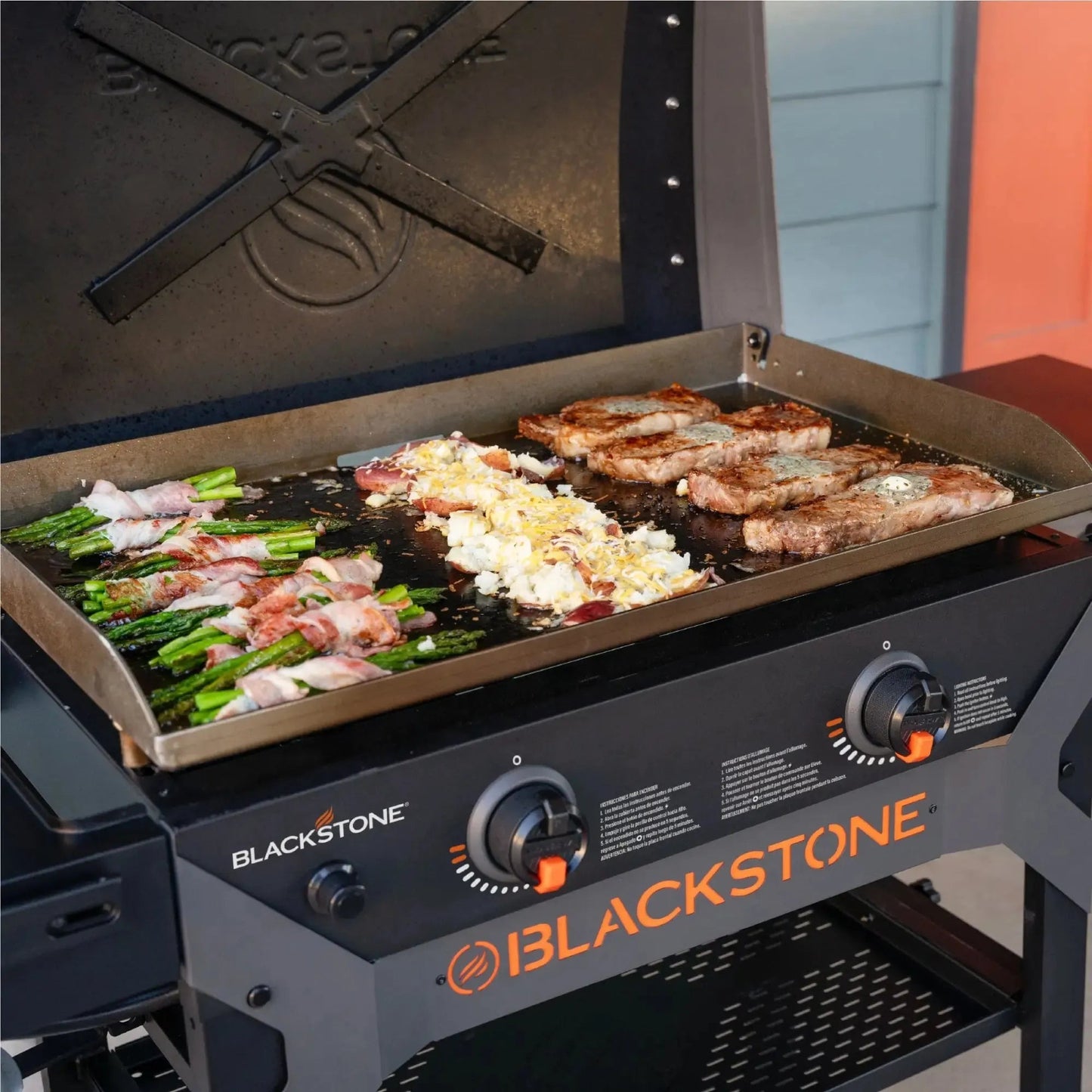 Blackstone iron forged 28 inch gas grill with flat top cooking surface black and orange accents with hood