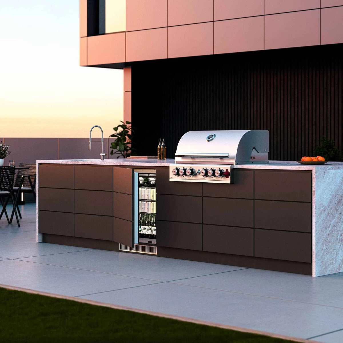 Stainless steel gas grill with sleek curved lid and red knobs mounted on outdoor kitchen island for blastcool extremis ixp1 fridge
