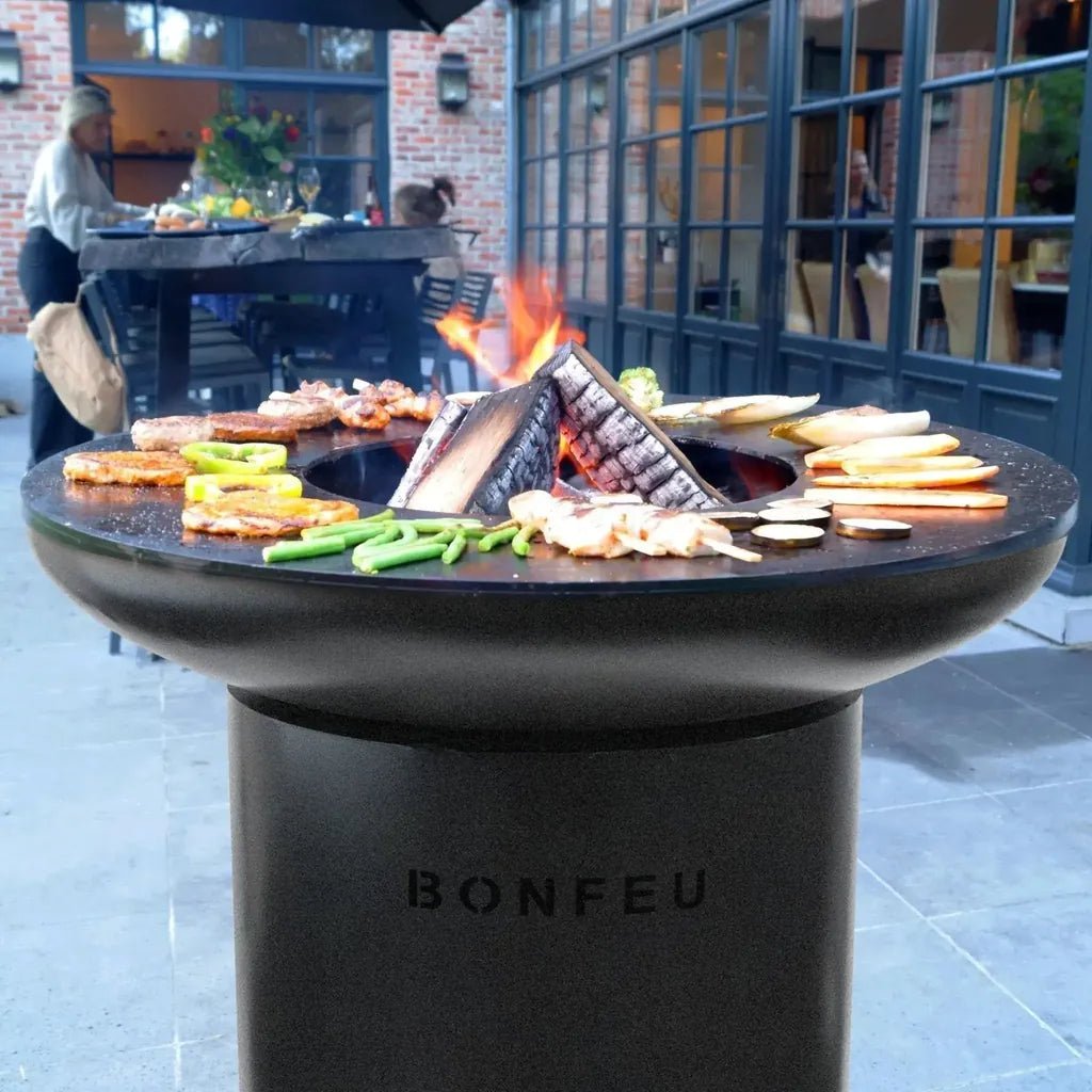 Black stone bonfeu bonbiza plancha grill fire pit with fire and food arranged around it for outdoor cooking