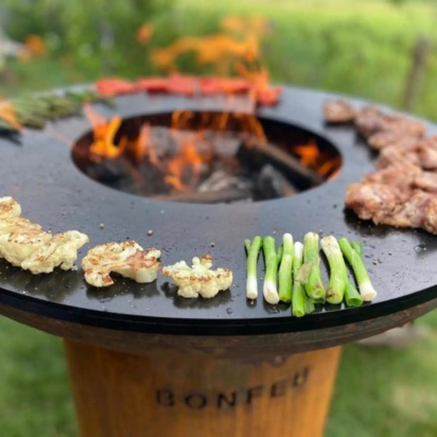 Black bonfeu bonbiza plancha grill fire pit with central fire and roasted cauliflower on its surface