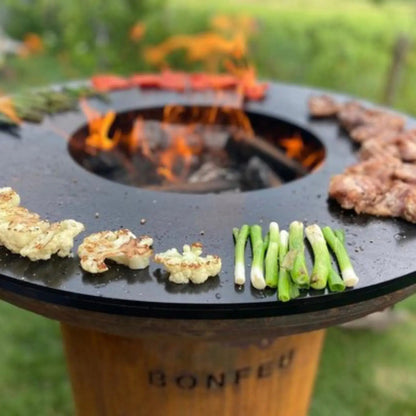 Black bonfeu bonbiza plancha grill fire pit with central fire and roasted cauliflower on its surface