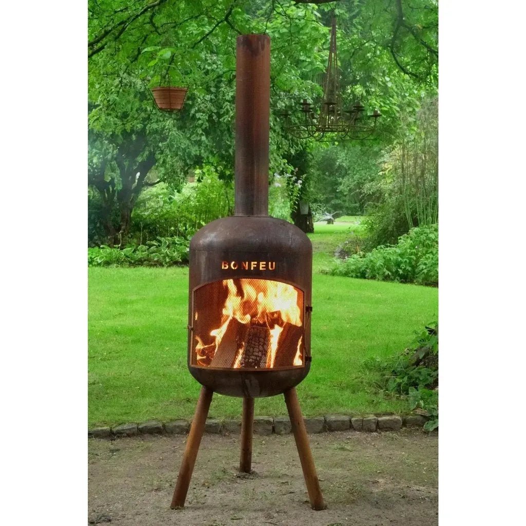 Rustic brown bonfeu bonbono large outdoor fireplace with tall chimney and tripod legs in corten steel with glowing fire