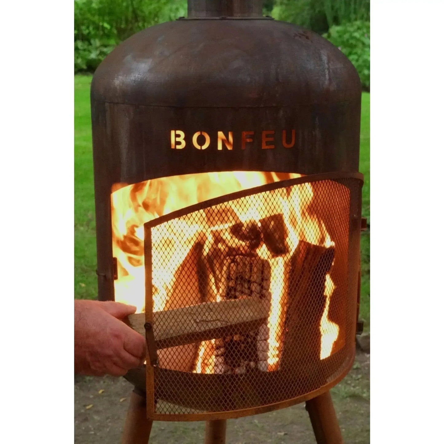Rusty metal bonfeu bonbono large outdoor fireplace with mesh screen and glowing flames in corten steel