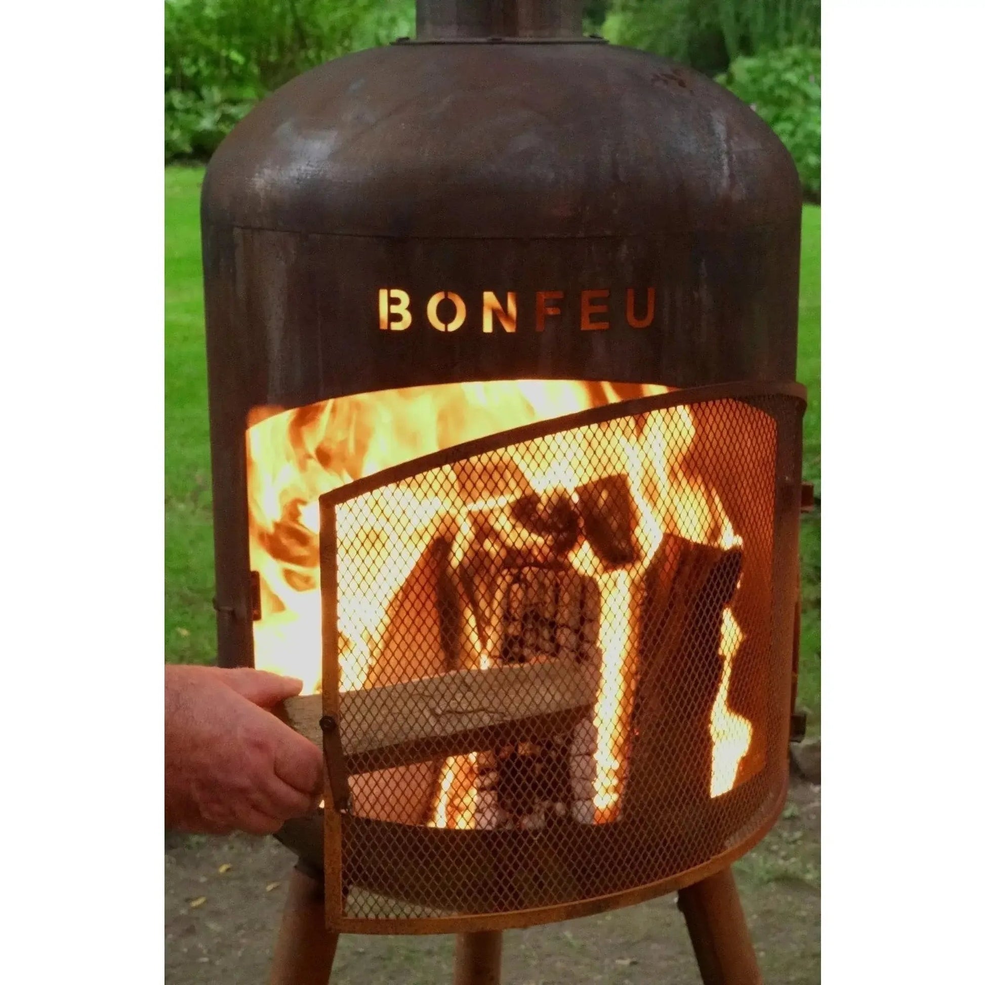Rusty metal bonfeu bonbono large outdoor fireplace with mesh screen and glowing flames in corten steel