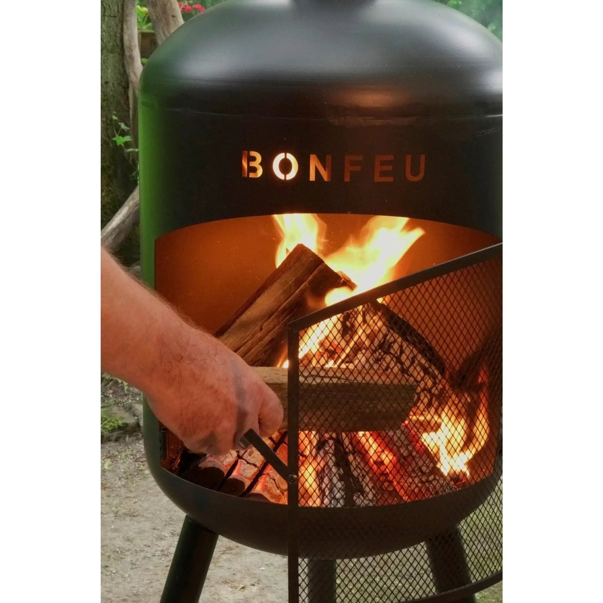 Black metal bonfeu bonbono large outdoor fireplace with mesh screen and glowing embers inside