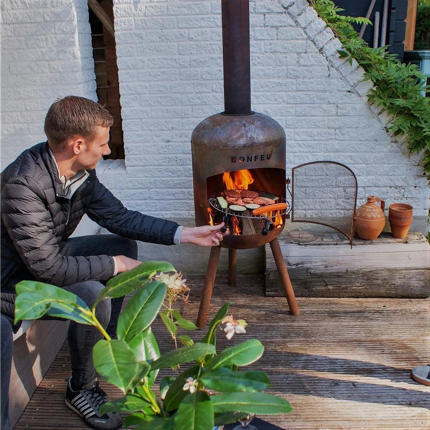 Rustic bonfeu bonbono large outdoor fireplace in black metal with tripod legs and chimney grilling food in open front