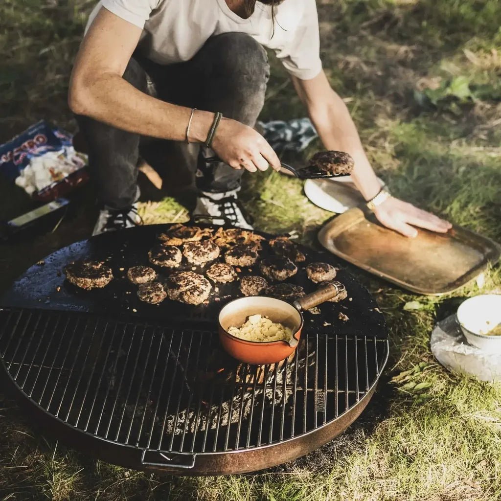 Round black cast iron grill with wire grate and glowing charcoal embers in bonfeu bonbowl corten steel fire bowl