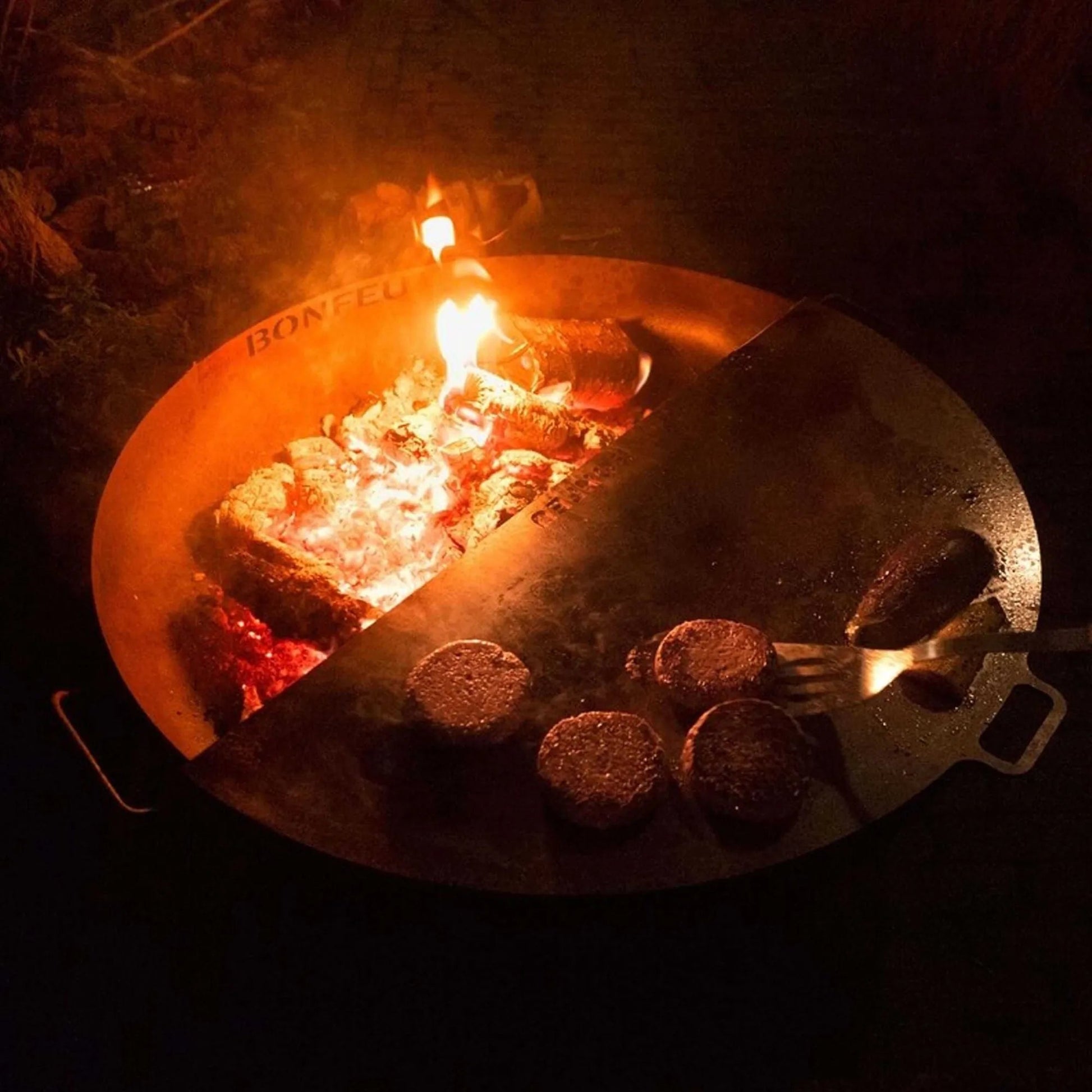 Bronze corten steel bonfeu bonbowl plus fire pit with split design showing embers and cooking burger patties