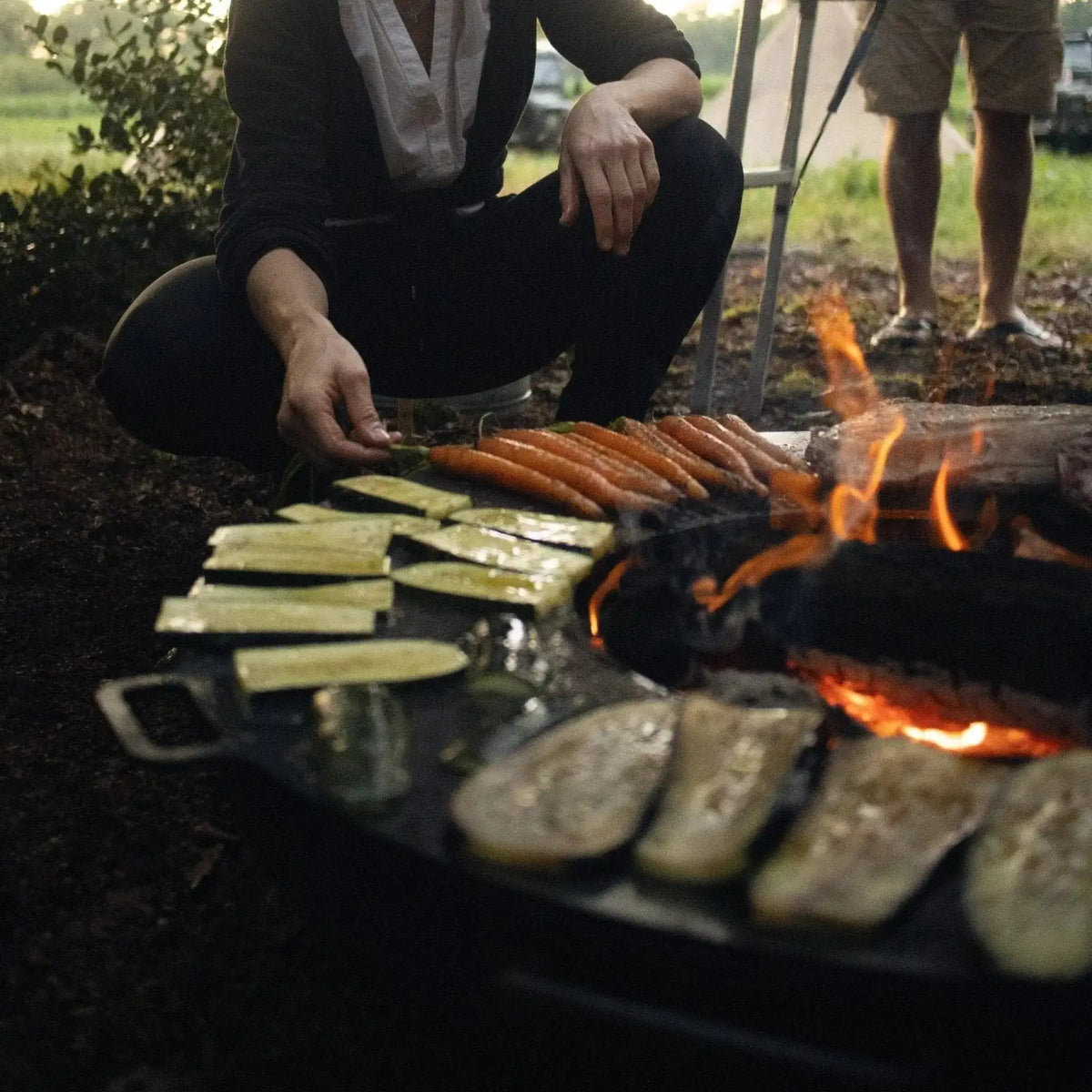 Black cast iron grill with vegetables sizzling over open flames on bonfeu bonbowl plus corten steel fire bowl