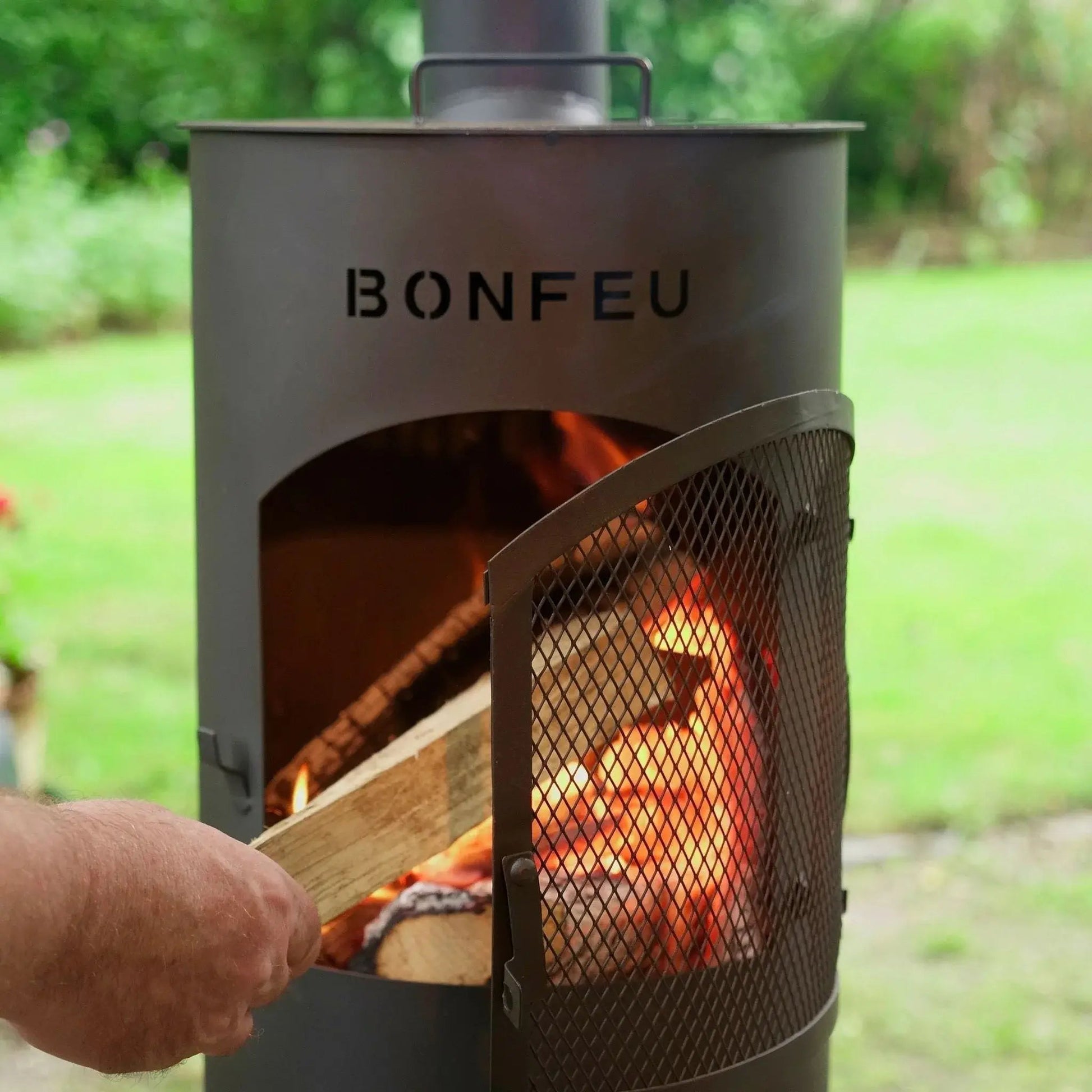 Gray metal bonfeu bongiano lp outdoor wood-burning stove with mesh door and visible flames in black and corten steel