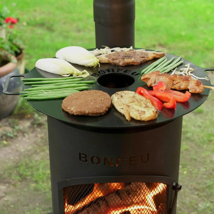 Black circular griddle with engraved branding and ventilation hole atop bonfeu bongiano lp outdoor fireplace in black steel
