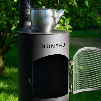 Silver metallic teapot resting on black bonfeu bongiano lp outdoor wood-burning stove in steel and corten finish