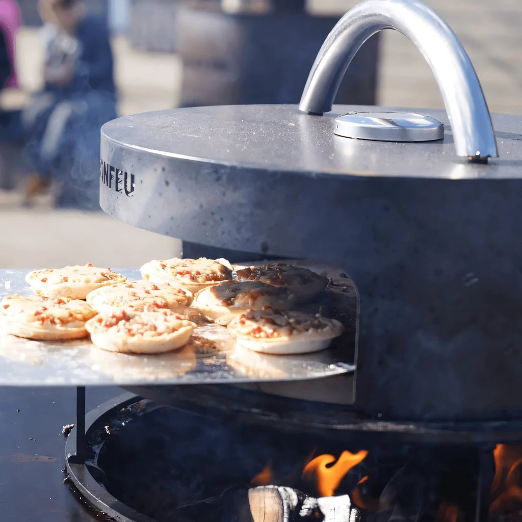 Silver-toned modern bonfeu bonpizza pizza oven with curved handle and visible flames beneath for outdoor cooking