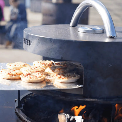Silver-toned modern bonfeu bonpizza pizza oven with curved handle and visible flames beneath for outdoor cooking