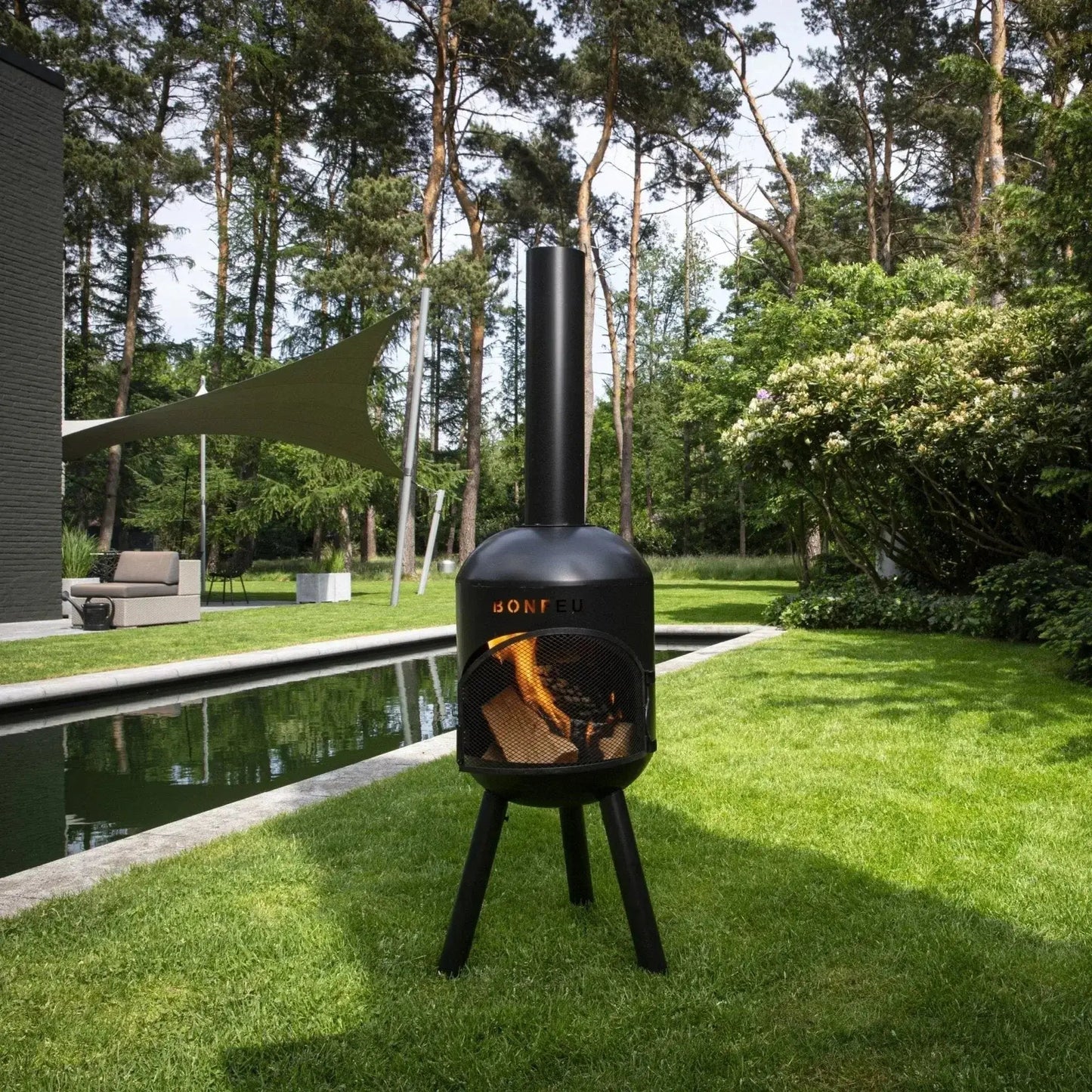 Black bonfeu bonsolo outdoor chiminea with tall cylindrical chimney tripod base and glowing logs inside