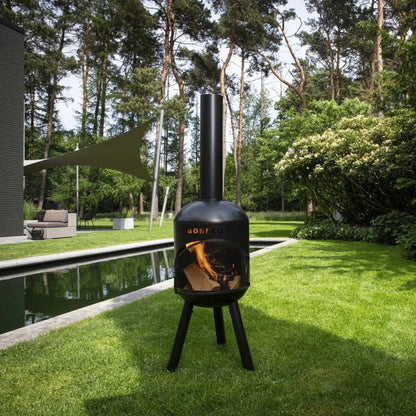 Black bonfeu bonsolo outdoor chiminea with tall cylindrical chimney tripod base and glowing logs inside