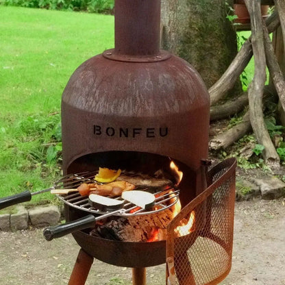 Rustic reddish-brown corten steel bonfeu bonsolo outdoor fireplace with round grill grate and mesh safety shield