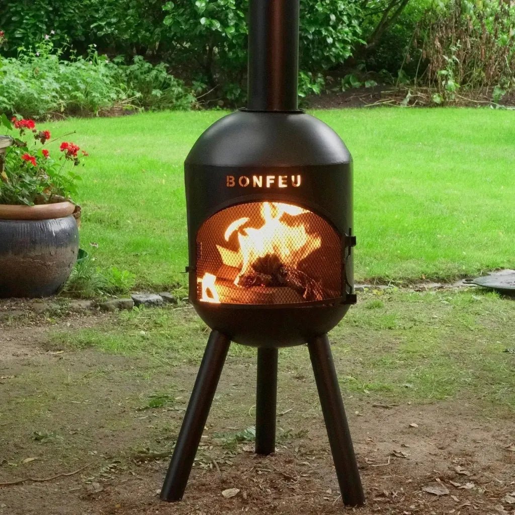 Black metal bonfeu bonsolo outdoor fireplace with glowing fire inside mesh-lined chiminea opening