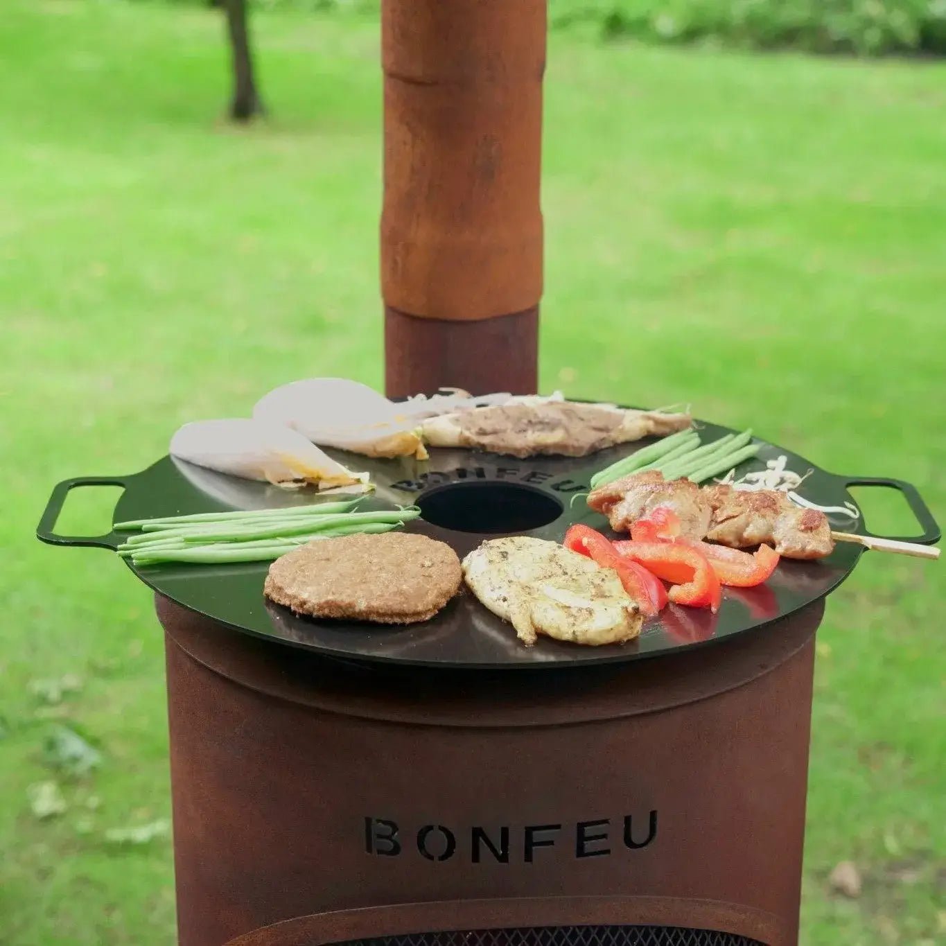 Black circular griddle with handles on rust-colored corten steel bonfeu bontino lp outdoor fireplace grill