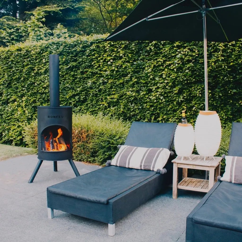 Black metal bonfeu bonton large outdoor fireplace with visible flames inside its cylindrical body made of steel